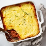 Torta de carne e batata em um refratário de cerâmica com o topo muito dourado e crocante, borbulhando nas pontas.